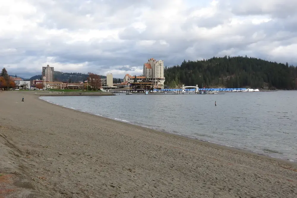 Sandy shore of Lake Coeur d'Alene with the downtown waterfront and marina in Coeur d'Alene, Idaho